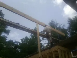 Carpenter setting a ridge beam over a new addition frame — Ice Dam Removal by Roofing Brothers in Brandon